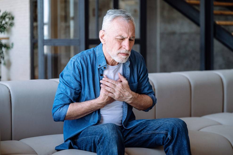 A person sitting on a couch holding his chest